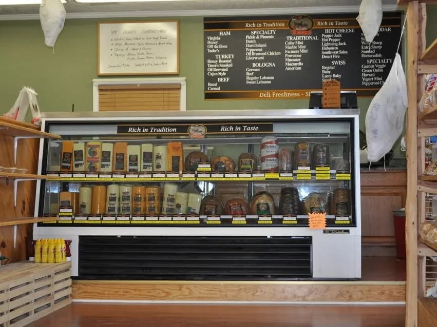 The store's original deli case, with a hand-lettered sandwich sign and the meats and cheeses board above it