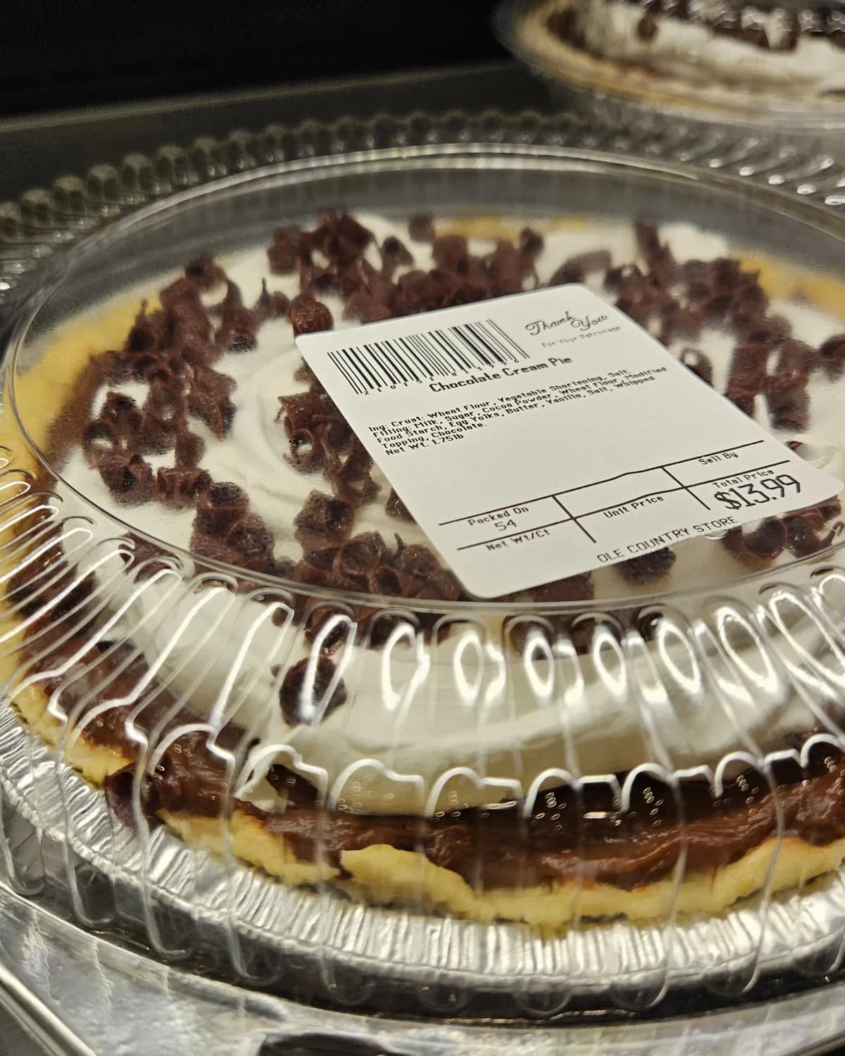 A chocolate cream pie topped with whipped cream and chocolate curls