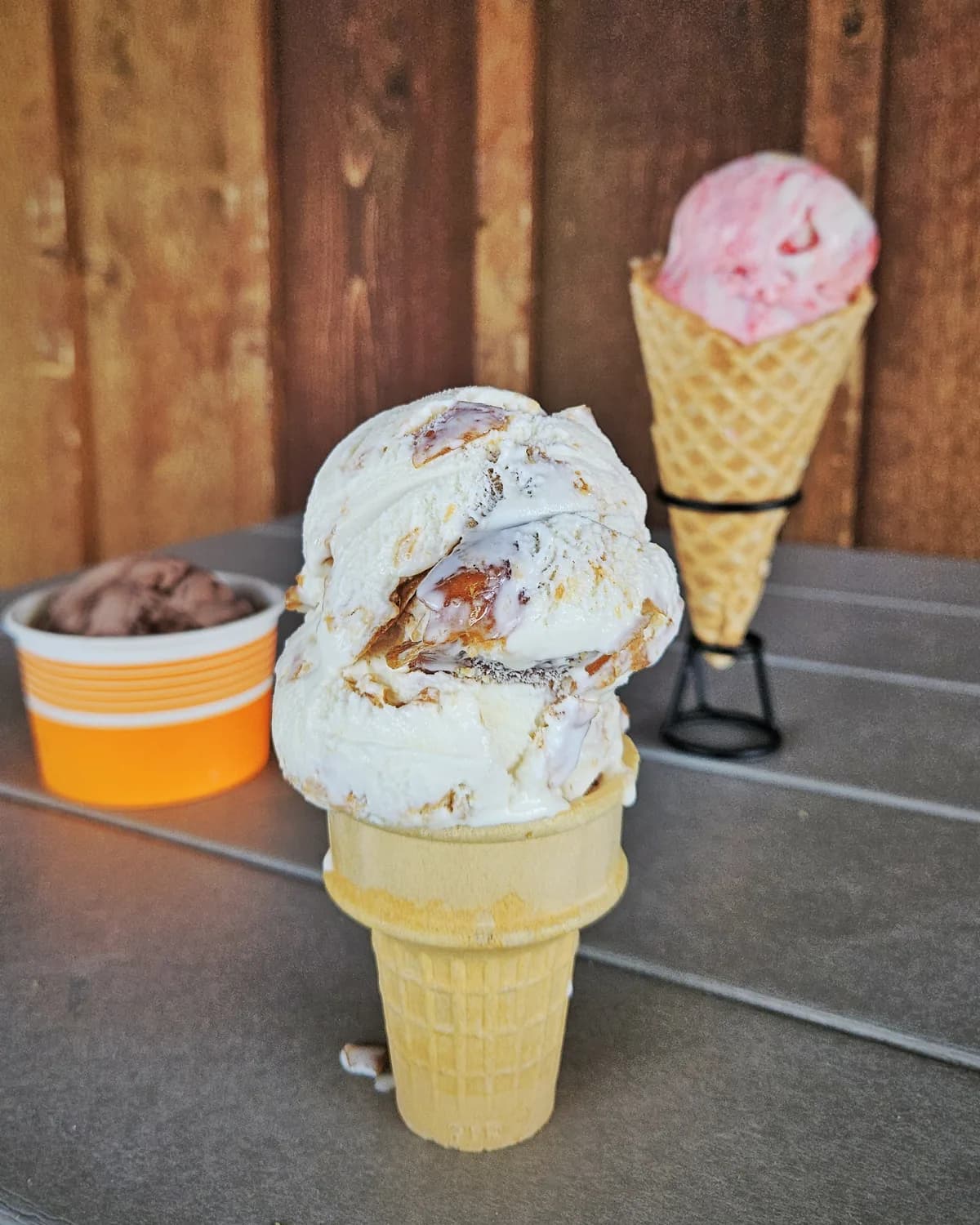 Waffle cones and a cup of ice cream on a table outside the creamery