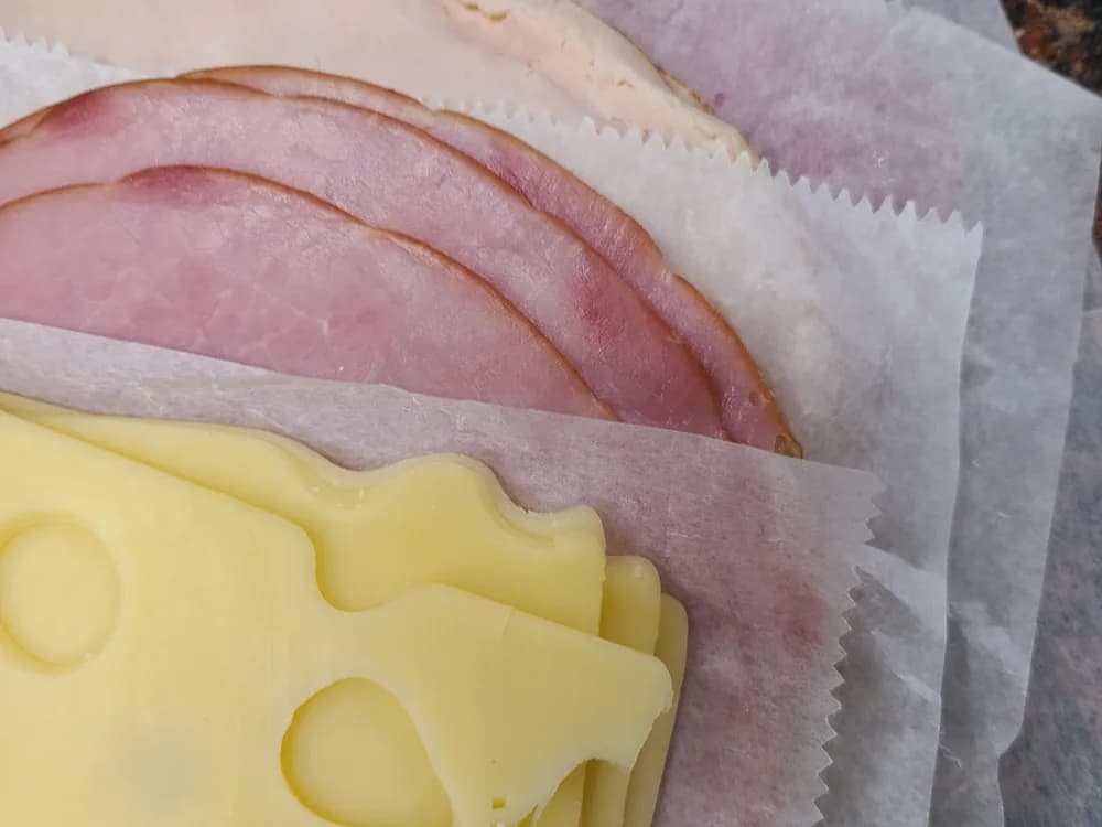 Sliced ham and Swiss cheese on deli paper