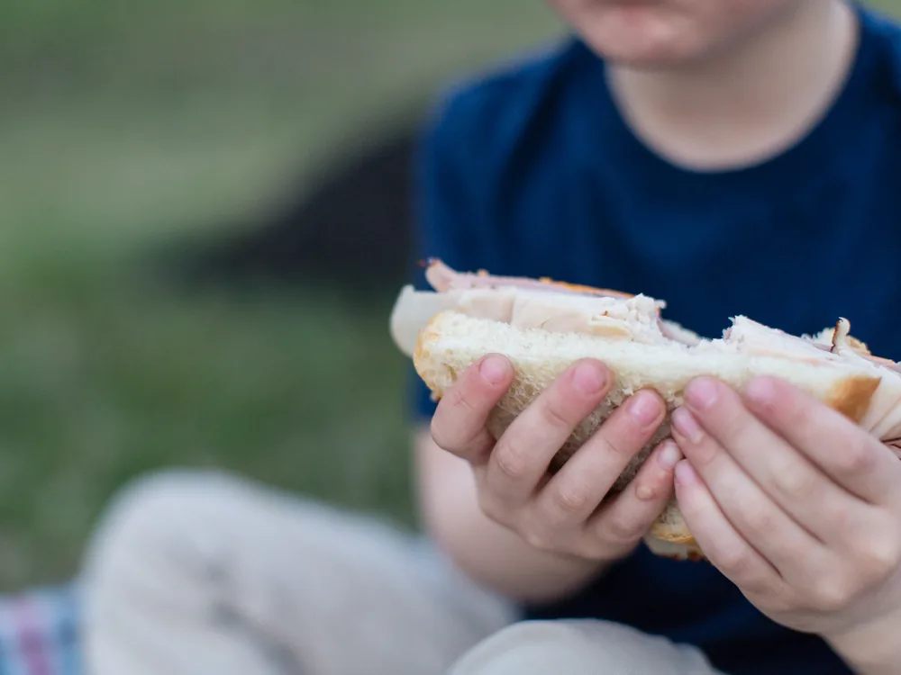 A child eating a sandwich from the deli